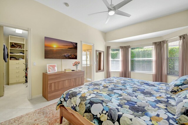 bedroom with light tile patterned floors, a spacious closet, multiple windows, and a ceiling fan