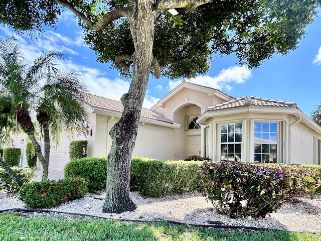 mediterranean / spanish-style house with an attached garage, a tile roof, and stucco siding