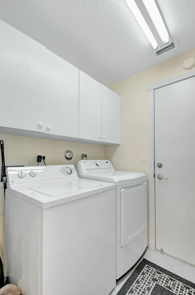 laundry area featuring cabinet space, visible vents, a textured ceiling, washing machine and dryer, and light tile patterned flooring