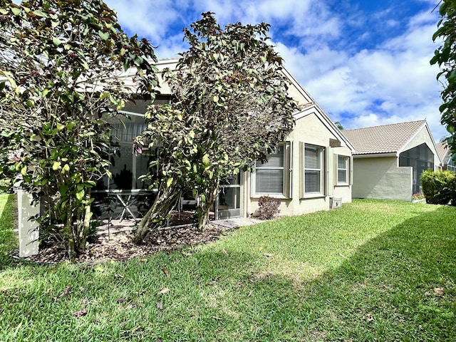 back of house with stucco siding, a tile roof, a patio area, and a yard