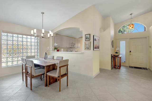 dining room with light tile patterned floors, high vaulted ceiling, baseboards, and an inviting chandelier