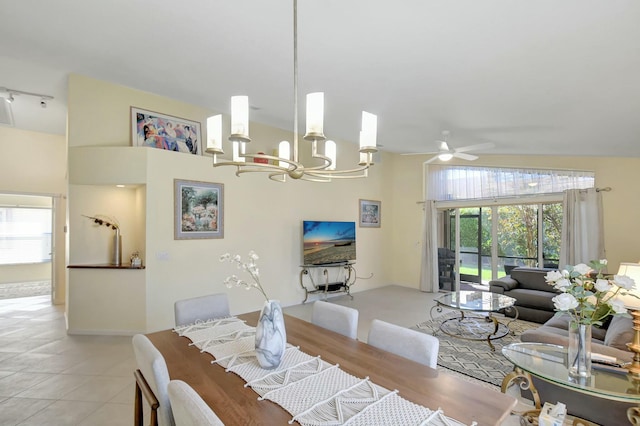 dining space with high vaulted ceiling, ceiling fan with notable chandelier, and light tile patterned flooring