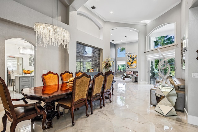 21741 Westmont Ct, Boca Raton, FL 33428 - dining room featuring arched walkways, a high ceiling, light marble finish floors, crown molding, and a chandelier