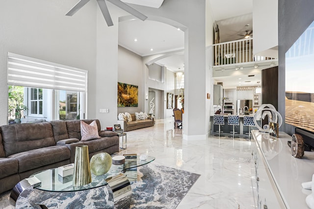21741 Westmont Ct, Boca Raton, FL 33428 - living room featuring a ceiling fan, a high ceiling, marble tiled floors, arched walkways, and crown molding