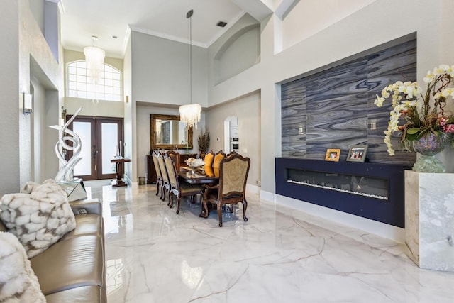 21741 Westmont Ct, Boca Raton, FL 33428 - dining area featuring a glass covered fireplace, crown molding, marble tiled flooring, a chandelier, and a towering ceiling