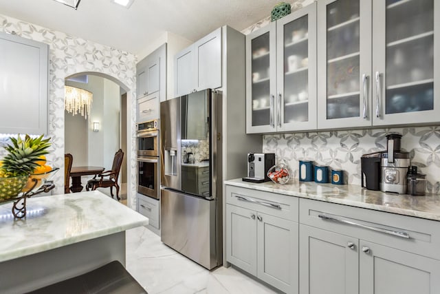 21741 Westmont Ct, Boca Raton, FL 33428 - kitchen featuring appliances with stainless steel finishes, light marble finish flooring, light stone countertops, gray cabinetry, and backsplash