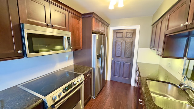 kitchen featuring a sink, dark wood-style flooring, dark stone counters, and stainless steel appliances