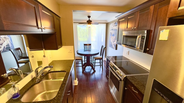 kitchen featuring appliances with stainless steel finishes, dark wood-style floors, a sink, a ceiling fan, and ornamental molding