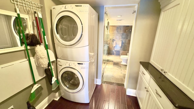laundry area with baseboards, stacked washer / drying machine, dark wood-style flooring, and laundry area