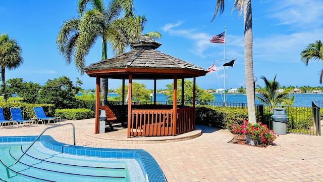 view of pool with a gazebo, a patio, a water view, and fence