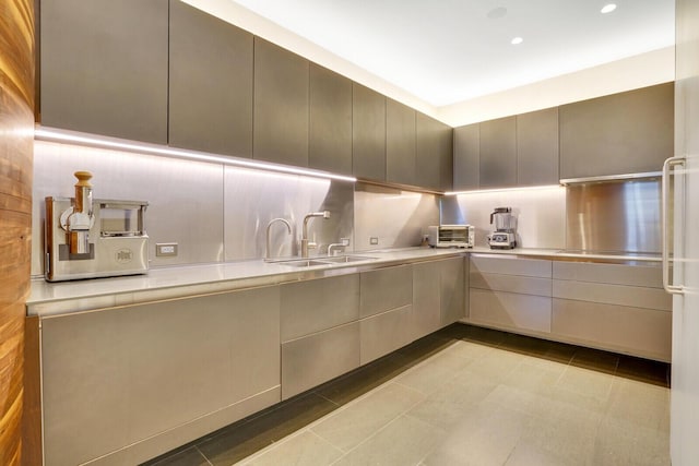 kitchen with tasteful backsplash, recessed lighting, light countertops, a sink, and modern cabinets