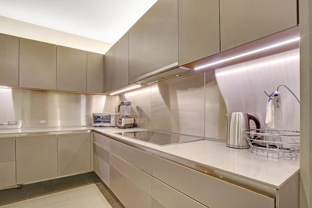 kitchen with light countertops, black electric stovetop, a toaster, and tasteful backsplash