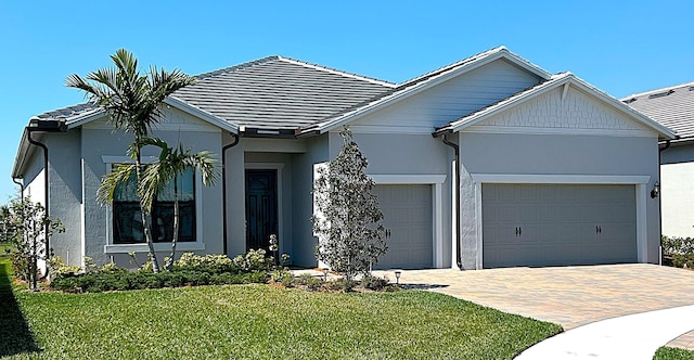 ranch-style house with a garage, decorative driveway, a front yard, and stucco siding