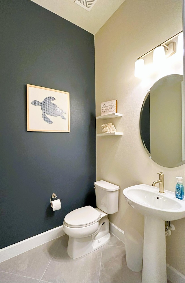 half bath with baseboards, a sink, toilet, and tile patterned floors