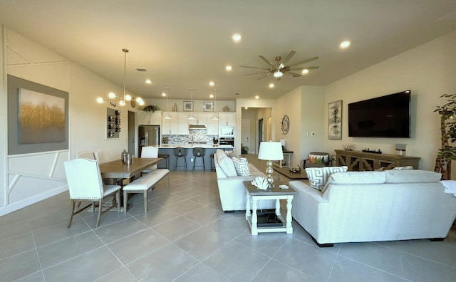 living area featuring recessed lighting, light tile patterned flooring, and ceiling fan with notable chandelier