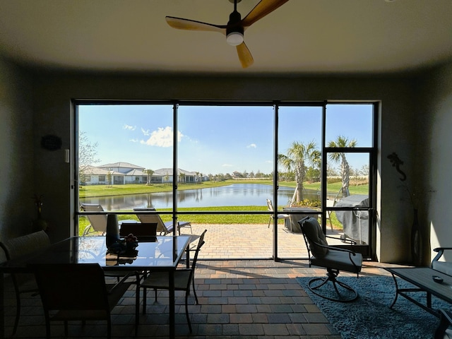 sunroom featuring a water view and ceiling fan