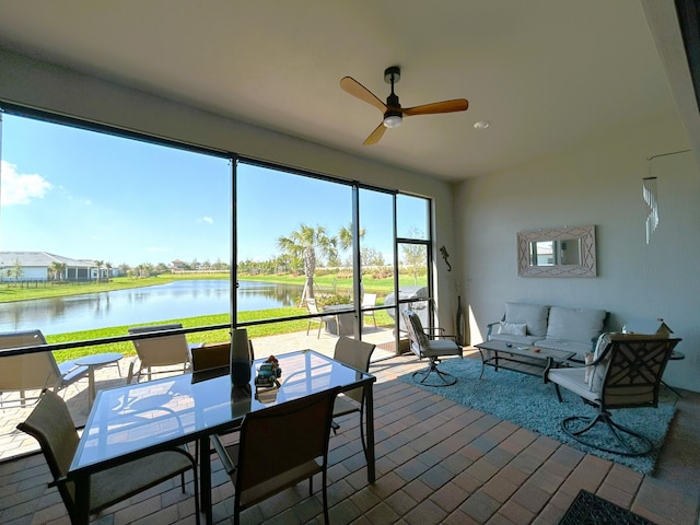 sunroom with a ceiling fan and a water view