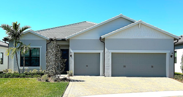 single story home with a garage, a tile roof, decorative driveway, and stucco siding