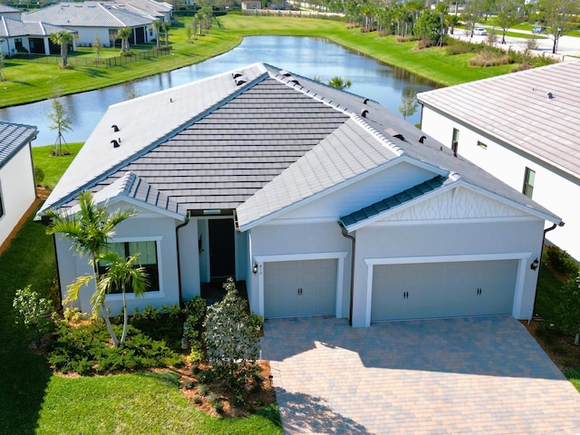 view of front facade featuring a garage, decorative driveway, and a water view