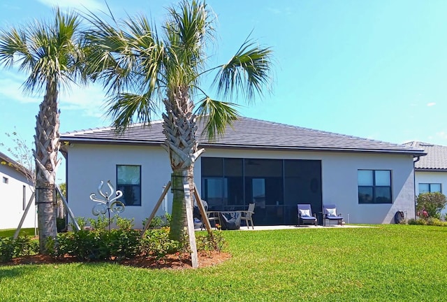 back of property featuring a yard, a tiled roof, a sunroom, and stucco siding