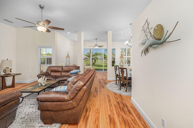 living room featuring light wood-type flooring, visible vents, vaulted ceiling, and baseboards