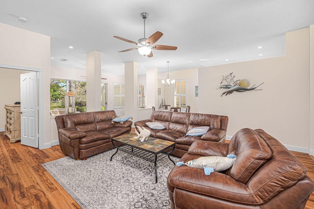 living area with ceiling fan with notable chandelier, baseboards, wood finished floors, and recessed lighting