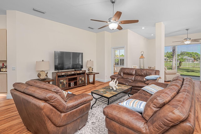 living room with baseboards, visible vents, ceiling fan, and light wood finished floors