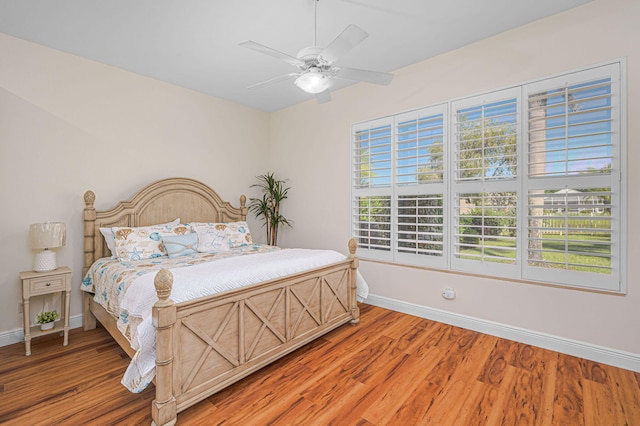 bedroom with ceiling fan, light wood-style flooring, and baseboards