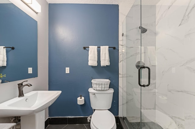 full bath with a marble finish shower, baseboards, a sink, and toilet