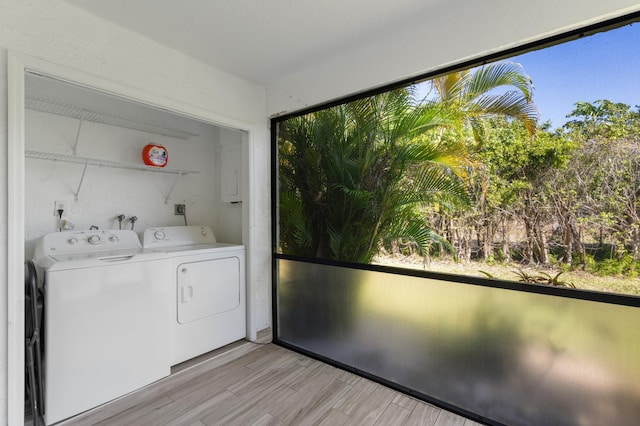 washroom with light wood-type flooring, laundry area, and washing machine and clothes dryer