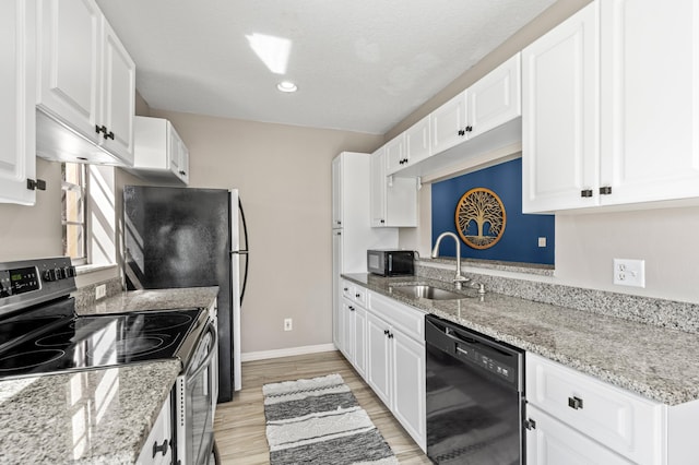 kitchen with light wood finished floors, baseboards, black appliances, white cabinetry, and a sink