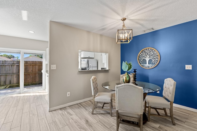 dining space with wood tiled floor, a textured ceiling, visible vents, and baseboards