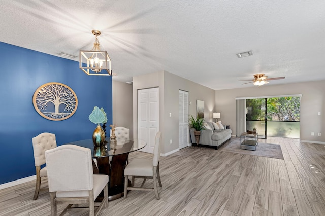 dining space with light wood-style floors, baseboards, visible vents, and a textured ceiling