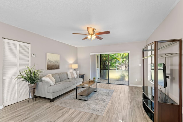 living area featuring light wood finished floors, baseboards, a ceiling fan, and a textured ceiling