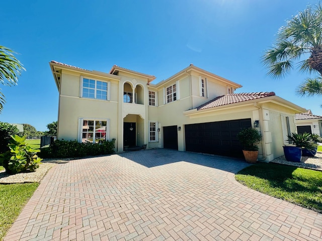 mediterranean / spanish-style home featuring stucco siding, decorative driveway, and a tiled roof