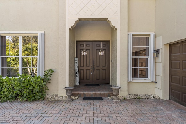 doorway to property with stucco siding and a garage