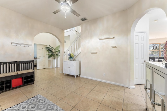 interior space with visible vents, arched walkways, light tile patterned flooring, baseboards, and ceiling fan