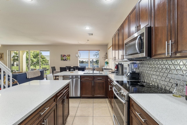 kitchen featuring visible vents, a peninsula, a sink, appliances with stainless steel finishes, and tasteful backsplash