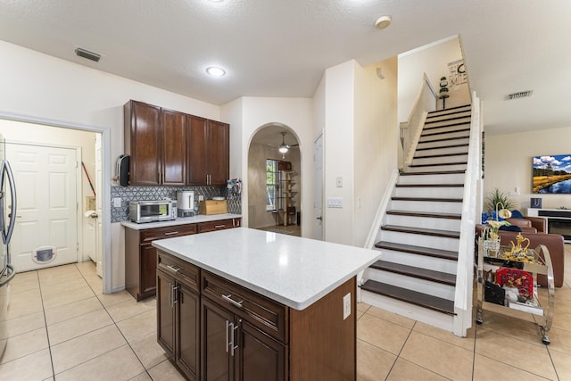 kitchen featuring arched walkways, visible vents, light countertops, and decorative backsplash