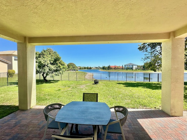 view of patio with a fenced backyard, a water view, and outdoor dining space