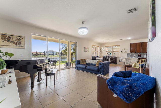 living room featuring light tile patterned floors, visible vents, and an inviting chandelier