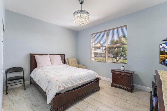 bedroom featuring an inviting chandelier, baseboards, and marble finish floor