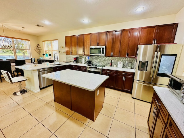 kitchen with light countertops, backsplash, appliances with stainless steel finishes, and a sink