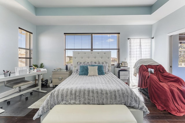 bedroom with a tray ceiling, baseboards, and dark wood-style flooring