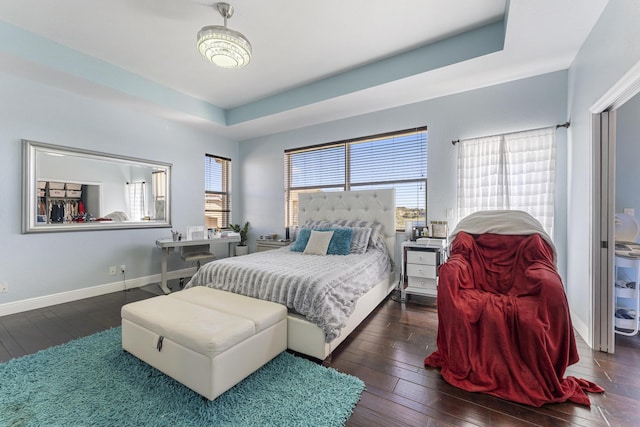 bedroom featuring a raised ceiling, baseboards, and hardwood / wood-style flooring