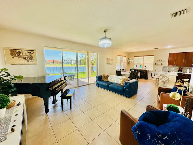 living area featuring light tile patterned floors, visible vents, and a water view