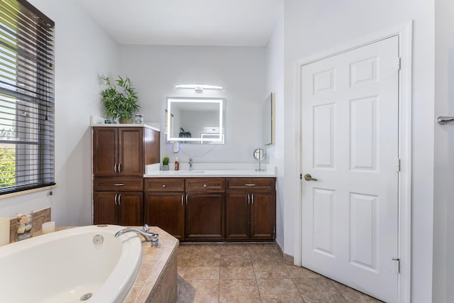 bathroom with a garden tub, vanity, and tile patterned flooring