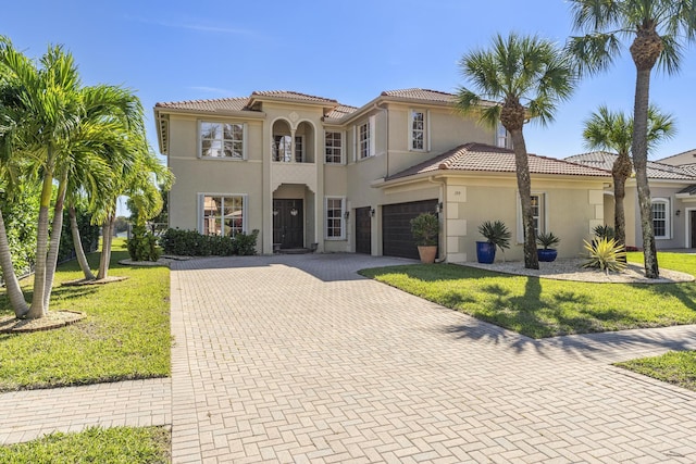 mediterranean / spanish-style house featuring stucco siding, decorative driveway, and a front yard