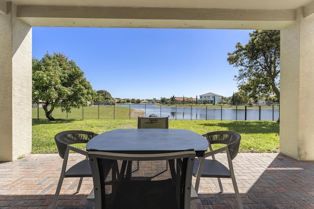 view of patio / terrace featuring outdoor dining area, a water view, and a fenced backyard