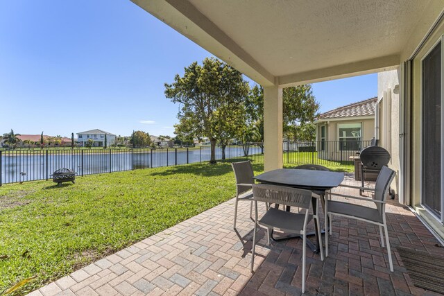 view of patio / terrace featuring outdoor dining space, a fenced backyard, and a water view